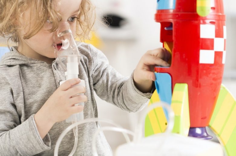 Child with cystic fibrosis using nebulizer playing with toy racket